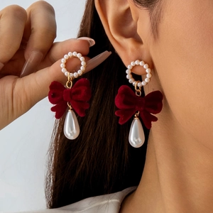 Close-up of red velvet bow earrings with teardrop pearls and vintage gold accents