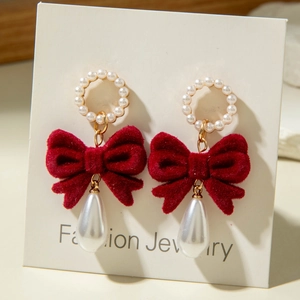 Detailed view of vintage earrings with red velvet bow and white drop pearl charms