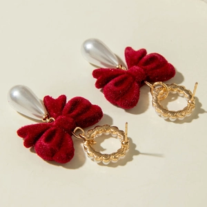 Detailed view of red velvet bow earrings with vintage pearls and golden floral rings