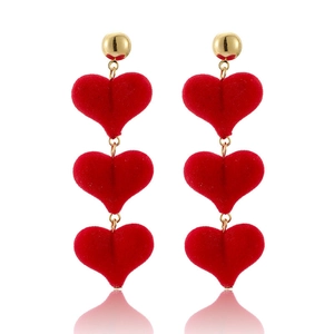 Detail view of triple red velvet heart drop earrings with golden spherical studs