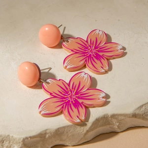 Pink cherry blossom acrylic drop earrings with gradient petals on stone background