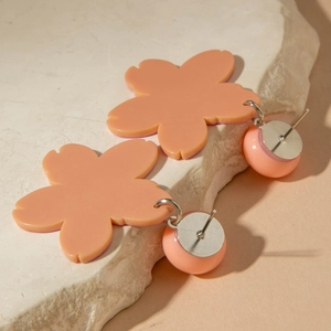 Macro shot of pink acrylic cherry blossom earrings with matte petals and matching beads