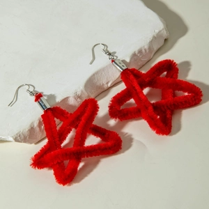 Close-up of red velvet star earrings with fluffy texture on white marble background