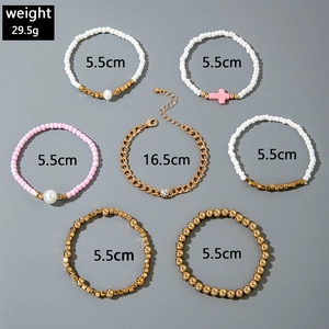 Dettaglio di un set di 7 bracciali a strati con ciondoli a cuore e croce dorati