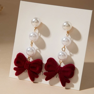Detailed view of red velvet bow earrings with three elegant faux pearls and gold hardware