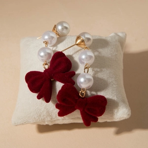 Detailed close-up of velvet bow earrings with pearls on a soft jewelry display pillow