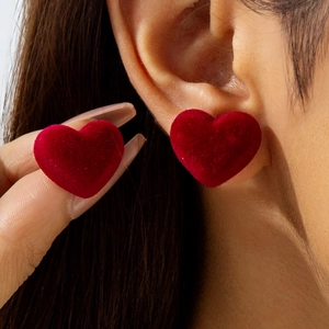 Close-up of red velvet heart stud earrings showing the soft flocked texture on ear
