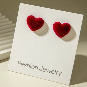 Close-up of red velvet heart earrings on white jewelry card for Valentine gift