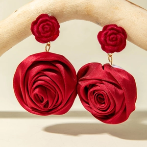 Macro detail of red velvet rose earrings with satin flower petals and golden ring links