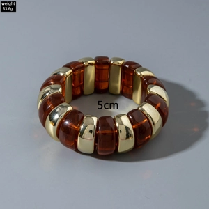 Detail of chunky amber resin and gold metal link bracelet showing 5cm width and weight