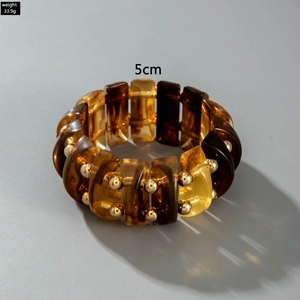 Macro view of retro acrylic curved bead bracelet with gold accents and amber marble texture