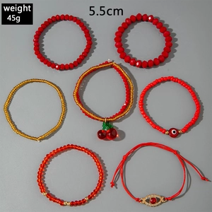 Detail of 7 red beaded bracelets with cherry charms and golden evil eye accents