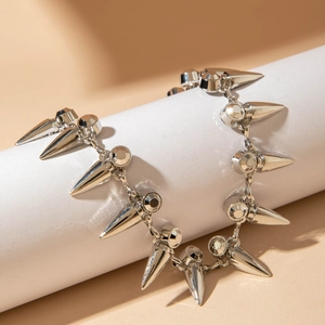 Punk silver necklace with polished metal spikes and faceted beads on a white pillar