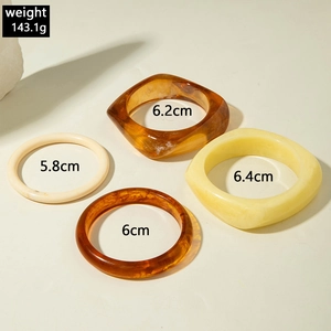 Flat lay of vintage resin bangles in amber and cream colors with size measurements