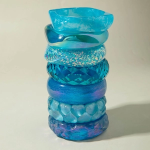 Stack of 7 blue resin bracelets featuring glitter, heart reliefs, and faceted designs