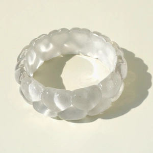 Détail du bracelet large en résine translucide avec texture à bulles gaufrée et fini mat