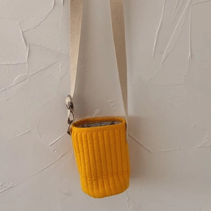 Close-up of a quilted bright yellow water bottle holder with an adjustable canvas strap