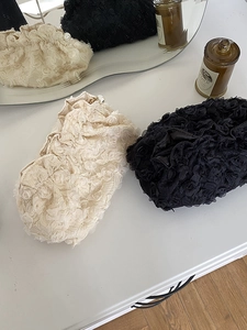 Detail of 3D lace floral makeup bags in beige and black with decorative pearl zippers