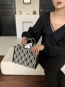 Vue détaillée du sac cabas en toile géométrique noir et blanc avec un smartphone
