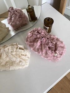 Close-up of elegant lace cosmetic bags with 3D floral petals and pearl zipper details