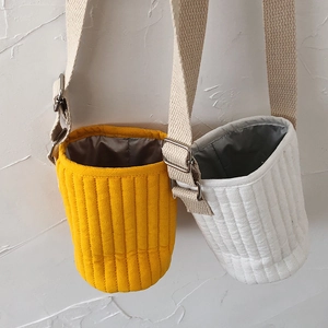 Close-up of quilted water bottle sleeves in yellow and beige with adjustable straps