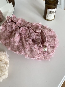 Detail of pink lace cosmetic bag featuring 3D floral petals and a pearl zipper pull