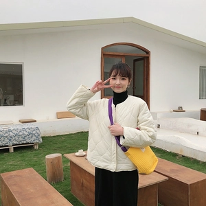Détail d'une veste matelassée blanche avec un petit sac bandoulière en toile jaune