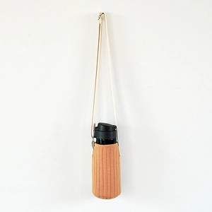 Detail of orange quilted water bottle sleeve with adjustable beige shoulder strap
