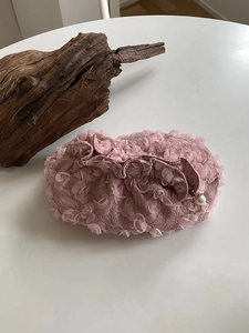 Detail of pink 3D flower petal lace makeup bag with pearl zipper pull on white surface