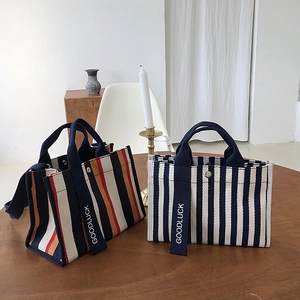 Détail de sacs fourre-tout en toile rayée avec broderie Goodluck et bouton-pression en métal