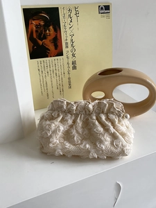 Detail of 3D rose lace clutch bag with elegant pearl zipper and cream floral texture