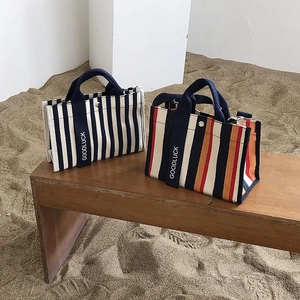 Vue détaillée des sacs cabas en toile rayée avec impression Goodluck sur les poignées