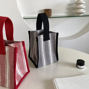 Detail of knitted canvas tote bags with striped patterns and wide durable handles