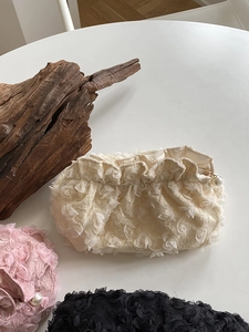 Detail of floral lace cosmetic bags in white, pink, and black with pearl zippers