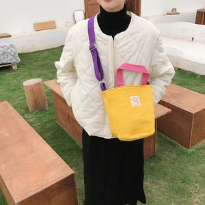 Détail du sac en toile matelassée jaune avec poignées roses et bandoulière violette