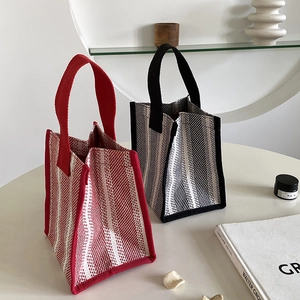 Close-up of knit tote bags with geometric texture in red and black on a white table