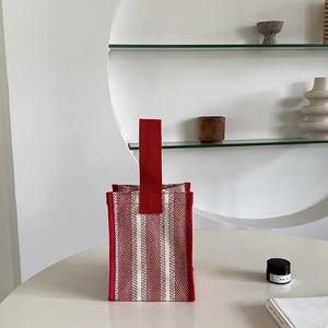 Detailed view of red and white striped canvas tote bag on a minimalist white table
