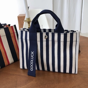 Détail d'un sac cabas en toile rayée avec sangle GOODLUCK et fermeture à bouton pression