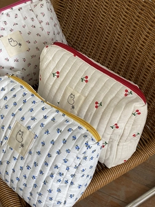Quilted cotton makeup bags with floral patterns and cherry prints on a vintage chair