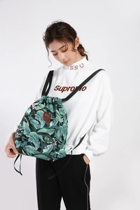 Detail eines Kordelzug-Rucksacks mit tropischem Blattmuster und Leder-Markenaufnäher
