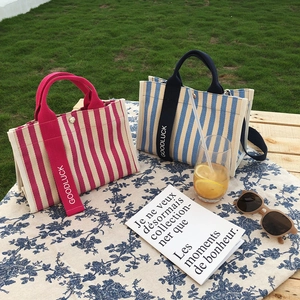Détail de sacs fourre-tout en toile rayée avec bouton métallique sur table de jardin