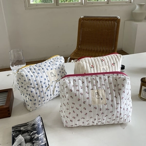 Three quilted cotton cosmetic bags with floral and cherry patterns on a white table
