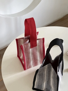 Close-up of minimalist canvas tote bags in red and black stripes on a white table