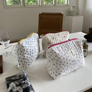 Detailed view of quilted cotton cosmetic bags in floral and cherry patterns on a table