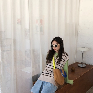 Sac bandoulière en toile marron porté avec un gilet en maille rayé et un short