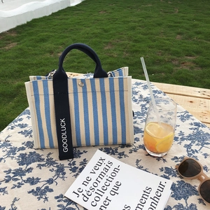 Sac cabas en toile à rayures bleues et blanches avec sangle Goodluck sur une table