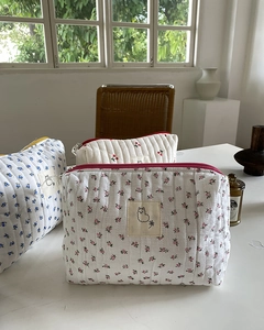 Detail of quilted cotton toiletry bags with floral and cherry prints and zip closure
