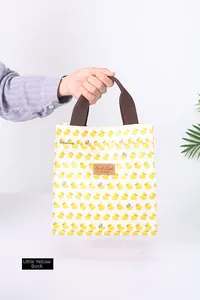 Detailansicht der gelben Enten-Schreibwarentasche mit braunen Griffen und Lederetikett