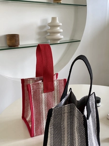 Close-up of minimalist striped canvas tote bags in red and black woven texture