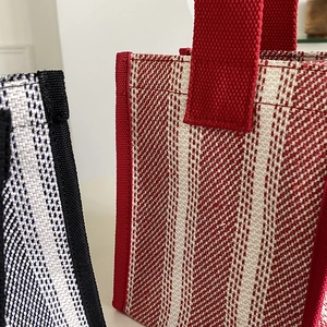 Close-up of durable woven canvas tote texture with sturdy handles and contrast stripes